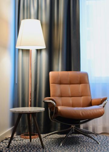 a brown chair sitting next to a table with a lamp at Quality Hotel Ålesund in Ålesund