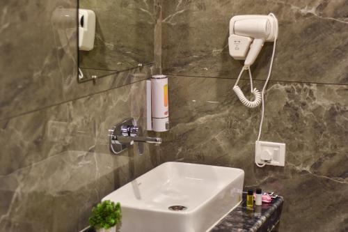 uma casa de banho com um lavatório e um telefone na parede em HOTEL YASH PALACE em Nova Deli