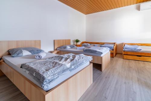 drie bedden in een kamer met houten vloeren bij Bed and Breakfast Špelca in Pivka