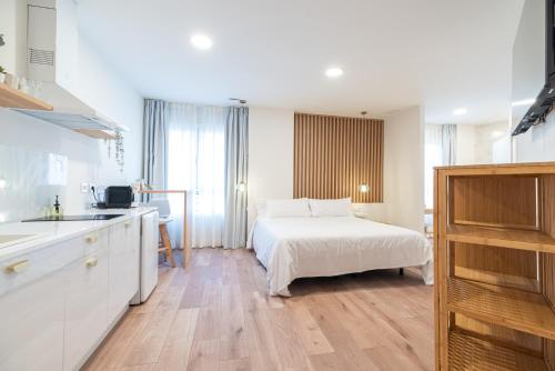 a white bedroom with a bed and a kitchen at Apartamentos turísticos Fátima, en el centro de Vigo in Vigo