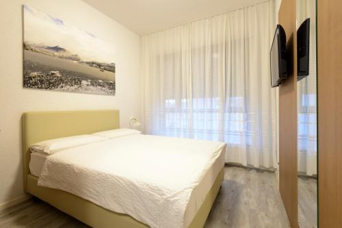 a white bedroom with a bed and a window at Hotel Ceresio in Lugano