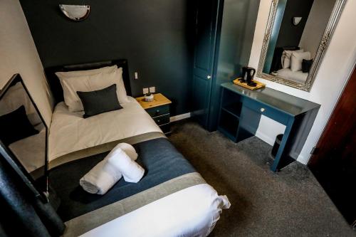 a small bedroom with a bed and a mirror at Cumbria Park Hotel in Carlisle