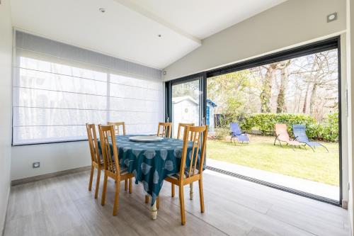 une salle à manger avec une table et des chaises et une fenêtre dans l'établissement Jardin et confort à 600m de la plage de la Jetée, à Andernos-les-Bains