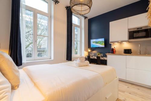 une chambre avec un grand lit blanc et une cuisine dans l'établissement Lille Center - Nice studio, à Lille
