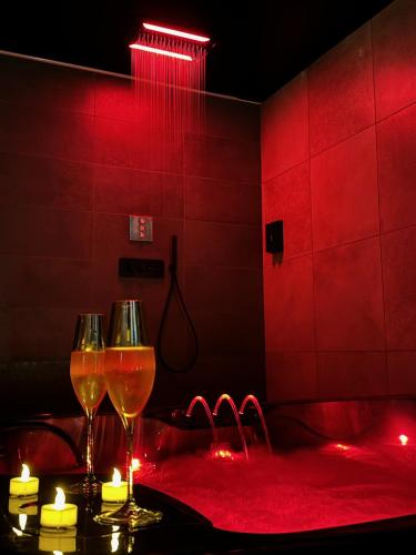 two wine glasses on a table in a room with red lights at Les secrets d'Eros - DAX in Dax