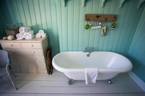y baño con bañera blanca y tocador. en Lulworth Cove Inn, en Lulworth Cove