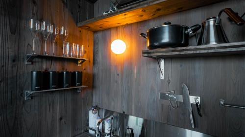 a kitchen with wooden walls and a light on the wall at Tiny N resort A棟 in Ichinomiya
