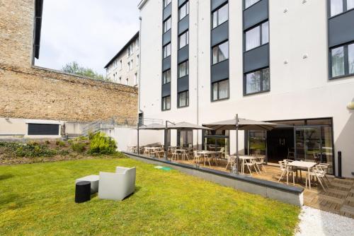 - une cour dans un bâtiment avec des tables et des chaises dans l'établissement Campanile Limoges Centre - Gare, à Limoges