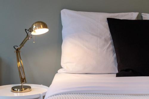 a bed with a lamp on a table next to a pillow at Lille Train station nice studio in Lille