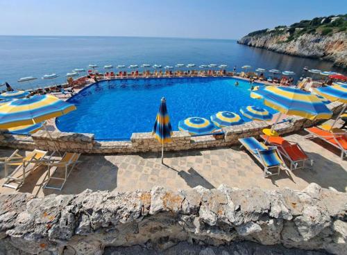 a swimming pool with umbrellas and chairs and the ocean at La Casetta 22 in Andrano