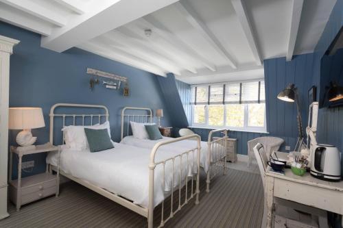 1 dormitorio con paredes azules y 1 cama en Lulworth Cove Inn, en Lulworth Cove