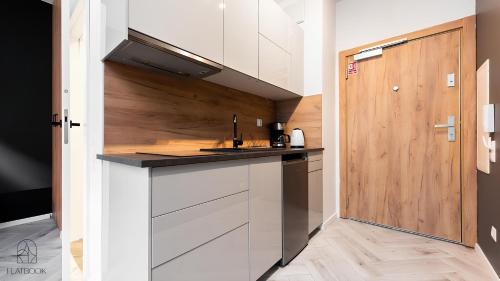a kitchen with white cabinets and a wooden door at Flatbook - City Center Apartments Waterlane Vintage with Gym in Gdańsk