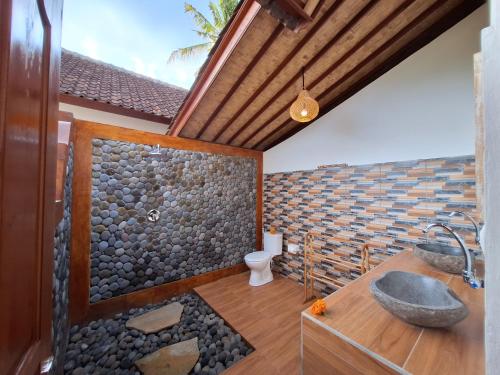 a bathroom with a sink and a stone wall at Frangipani Inn & Restaurant in Seraya