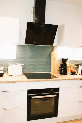 a kitchen with a stove and a microwave at Les Blés Dorés et Les Graines de Lin, 2 gîtes à la Ferme avec moutons et piscine, à côté de Beaune in Corgengoux