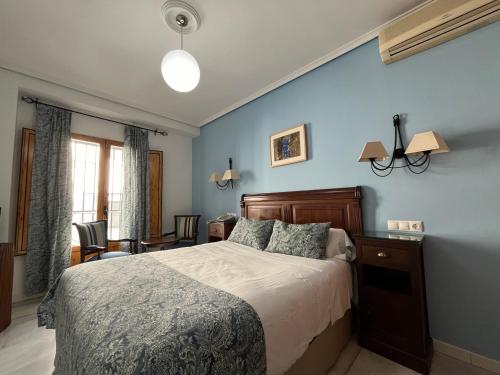 1 dormitorio con cama y pared azul en Hotel Maestre, en Córdoba