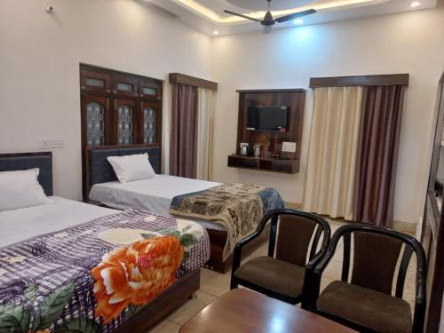 a hotel room with two beds and a table and chairs at Kalash Guest House in Ayodhya