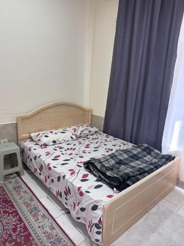 a small bed in a room with a bedspread on it at Studio for rent in Ajman 