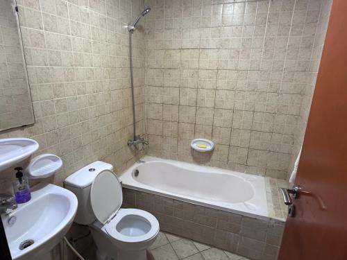 a bathroom with a tub and a toilet and a sink at Studio for rent in Ajman 