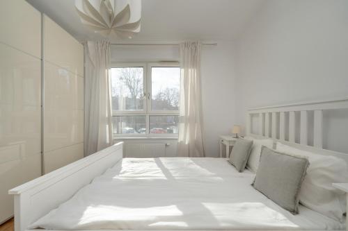 Cama blanca en habitación blanca con ventana en Black and Brown Apartment with Free Parking and Furnished Balcony in Wrocław by Renters en Breslavia