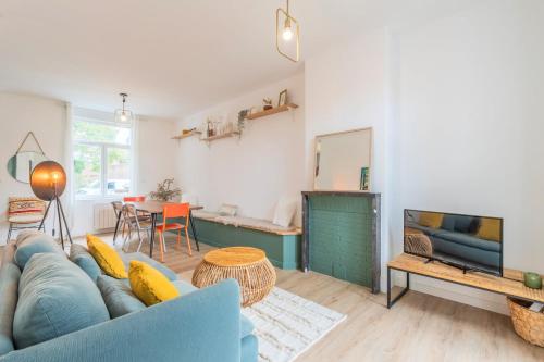 uma sala de estar com um sofá azul e uma televisão em 4 bedroom house with garden em Marcq-en-Baroeul