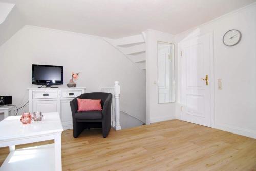 uma sala de estar branca com uma cadeira e uma televisão em Olympia Haus 1, Whg 3 em Westerland
