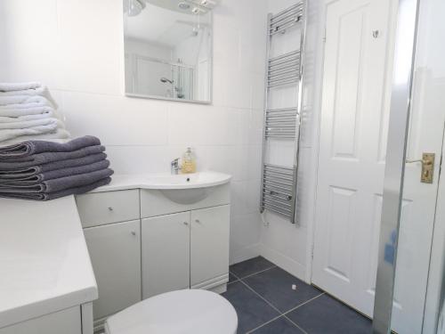 a white bathroom with a sink and a shower at Sandy Toes in Swanage