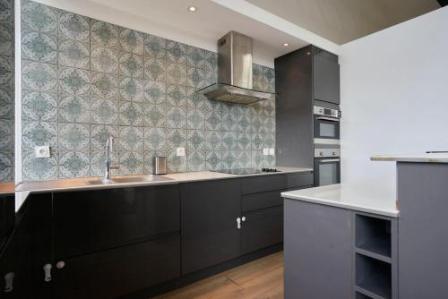 een keuken met zwarte kasten en een wastafel bij Loft en duplex atypique 4ch + parking in Tourcoing