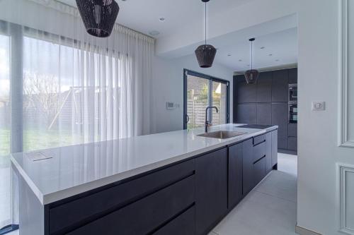 une cuisine avec un évier et une grande fenêtre dans l'établissement Les Nénuphars - Piscine et salle de sport équipée, à Dunkerque