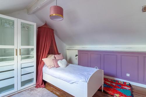 een slaapkamer met paarse muren en een klein bed bij Les Nénuphars - Piscine et salle de sport équipée in Duinkerke