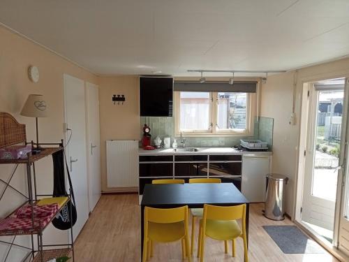 a kitchen with a table and yellow chairs in it at tiny house nabij de kust in Dirkshorn