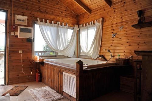 a bath tub in a wooden room with a window at The Edge Of The Village - Shefer in Shefer