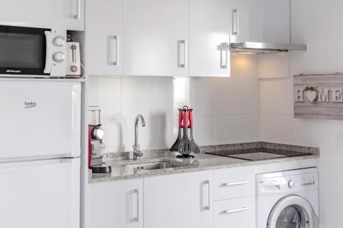 a white kitchen with a sink and a microwave at Cala en Forcat in Cala en Forcat