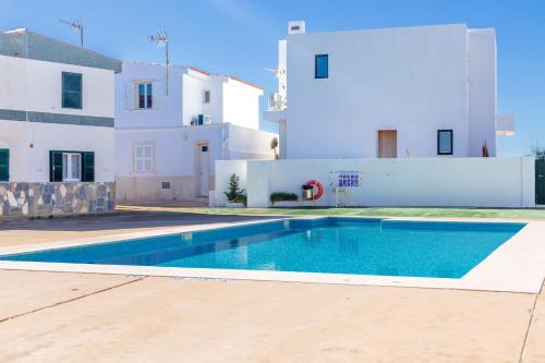 a villa with a swimming pool in front of a house at Cala en Forcat in Cala en Forcat