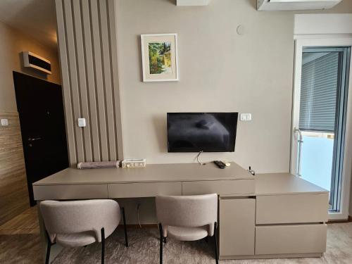 a desk with two chairs and a television on a wall at AGAPE Apartment in Podgorica