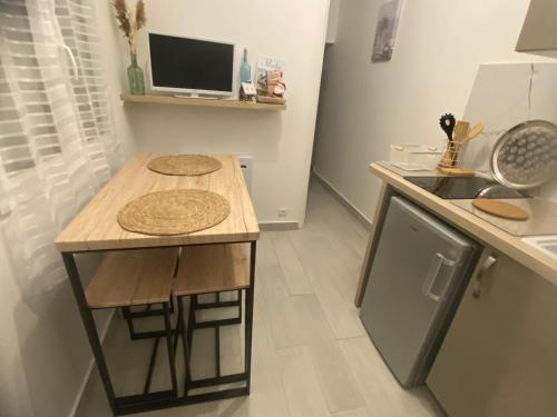 uma pequena cozinha com uma mesa e um lavatório em Maisonnette cocooning em Nogent-le-Rotrou