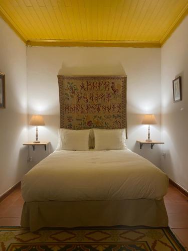 a bedroom with a large white bed with two lamps at Casa da Galega in Golegã