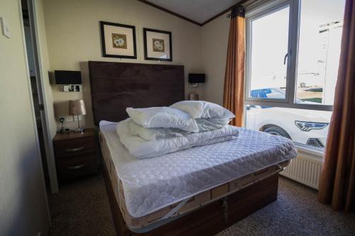 1 dormitorio con cama con almohadas y ventana en Stunning Caravan With Full Sea Views At Hopton Haven Ref 80044s en Great Yarmouth