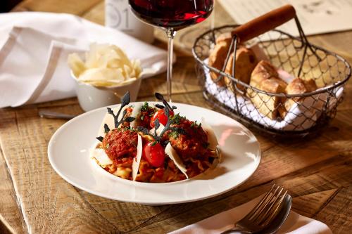 a plate of food on a table with a glass of wine at Hôtel L'Arboisie in Megève