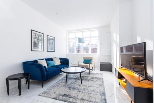 a living room with a blue couch and a tv at Luxury Harley Street Apartments in London
