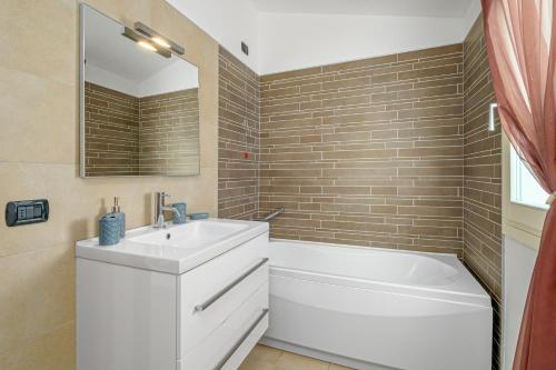 y baño con lavabo blanco y bañera. en Villa Marconi Apartment 12 attico, en Golfo Aranci
