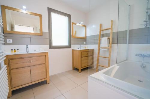 uma casa de banho com uma banheira, um lavatório e um espelho. em Pyla Belle villa au calme Proche plage em Pyla-sur-Mer