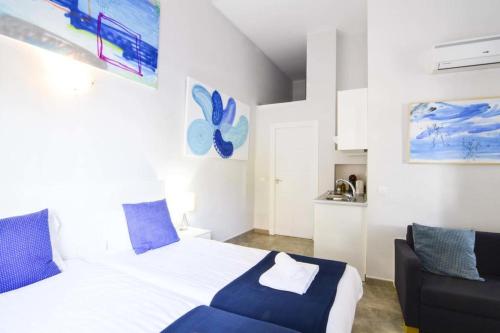 a bedroom with a white bed and a blue chair at ENJOY CAPUCHINOS in Málaga