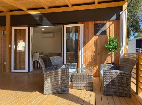 een terras met rieten stoelen en een tafel bij Oliva Mobile Home in Biograd na Moru
