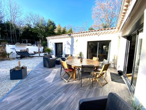 a patio with a wooden table and chairs at VILLA haut de gamme 6-8p, 3 ch, 3 sdb, piscine et superbe jardin clos in Saint-Sernin