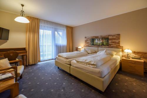 a hotel room with two beds and a large window at Landhaus Preißinger in Warmensteinach