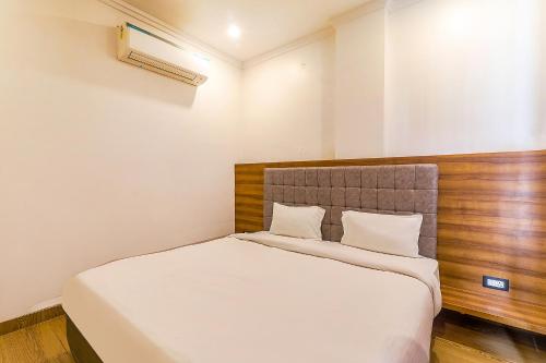 a bedroom with a large bed with a wooden headboard at FabExpress Global Inn New in Lucknow