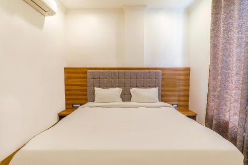 Schlafzimmer mit einem großen weißen Bett und Vorhängen in der Unterkunft FabExpress Global Inn New in Lucknow