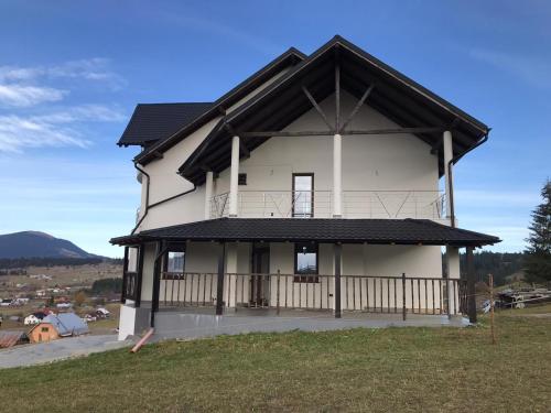a large white house with a black roof at VILA DE PE DEAL in Poiana Stampei