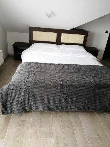 a bedroom with a large bed and a wooden floor at VILA DE PE DEAL in Poiana Stampei