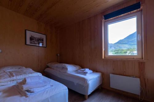 two beds in a room with a window at Modern Rorbu Ryten 1 in Sund